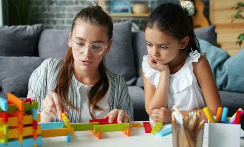 طفلة تلعب بألعاب تعليمية منزلية مع والدتها لتنمية مهارات التعلم والتركيز